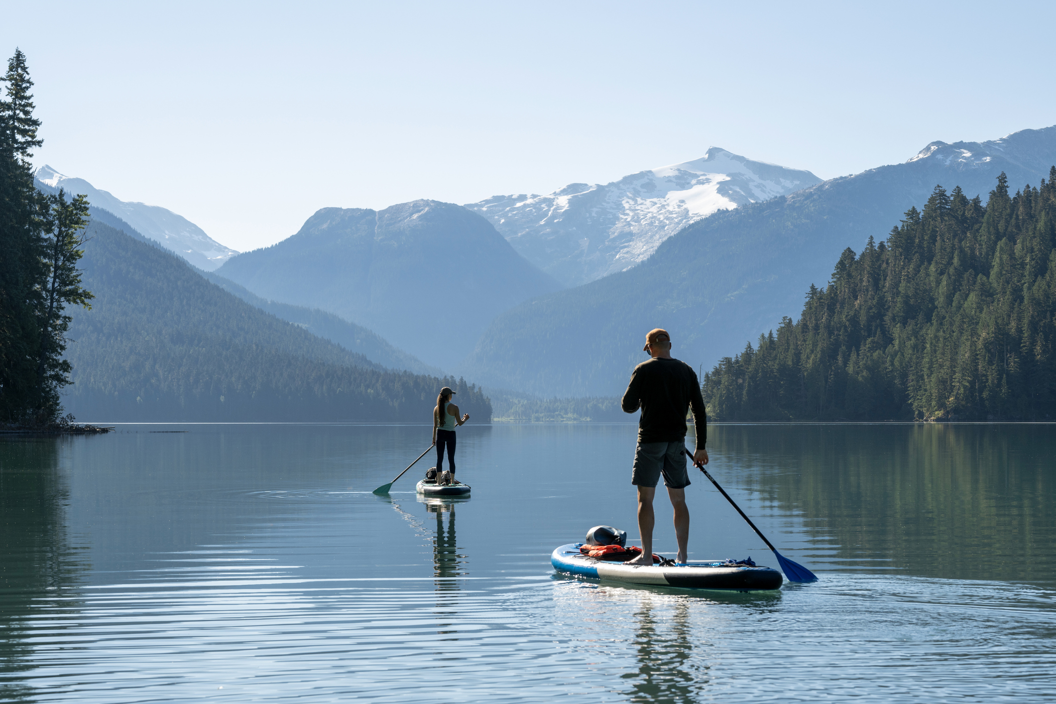 A wealthier life begins with purpose, symbolized by paddleboarding on a peaceful mountain lake.